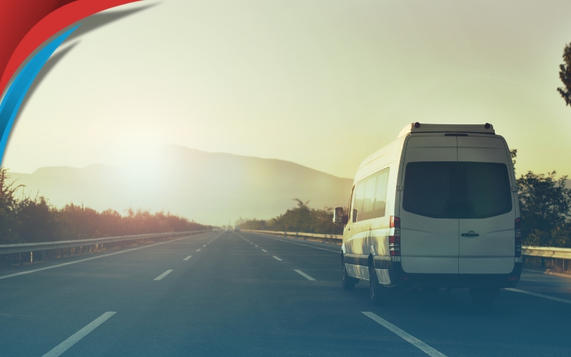 A comfortable minibus travels through a scenic landscape, with passengers enjoying the view.